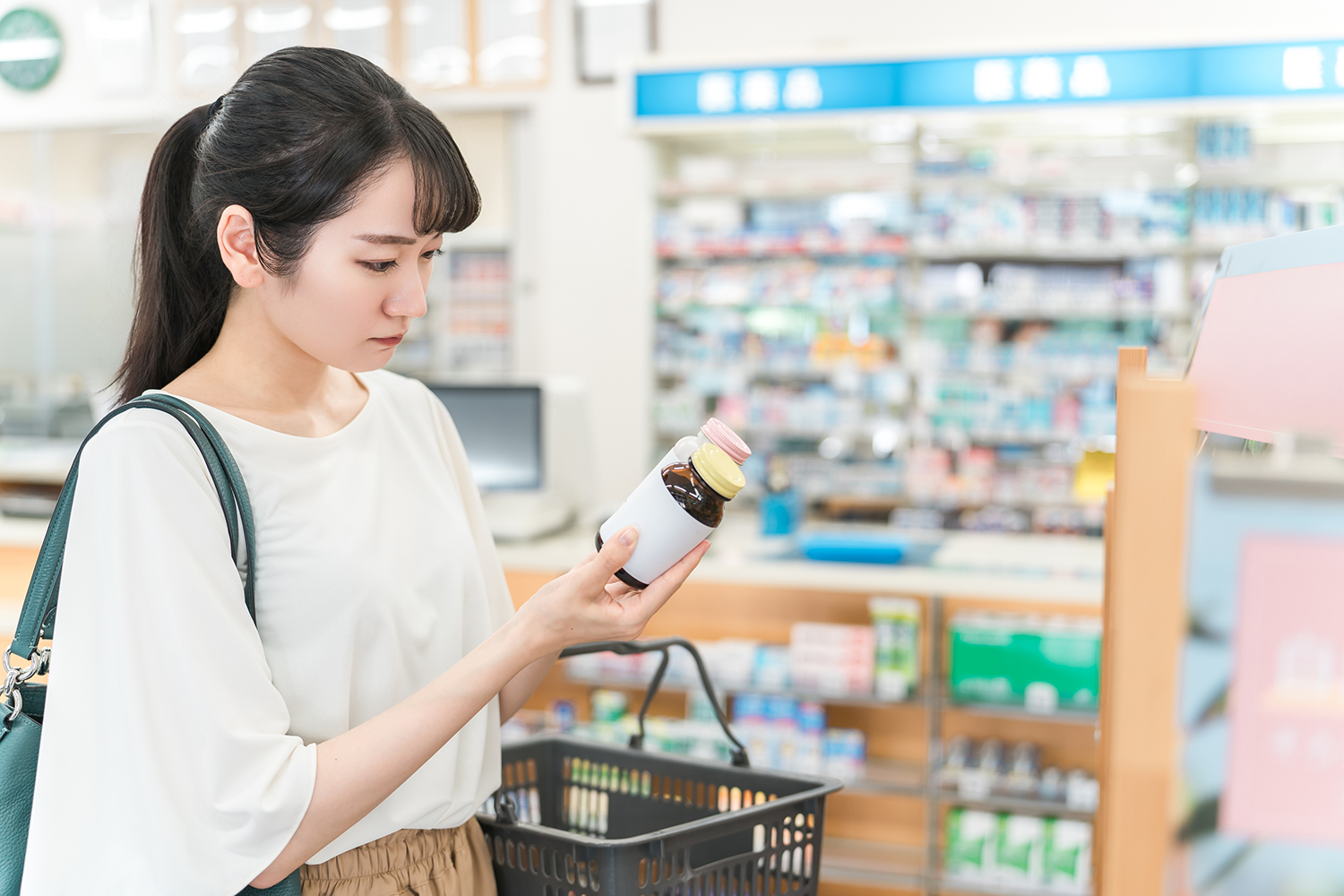 薬剤の入った瓶のラベルを確認している買い物中の女性の画像