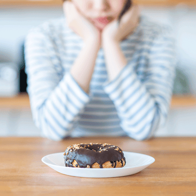 おやつを食べるのを悩む女性