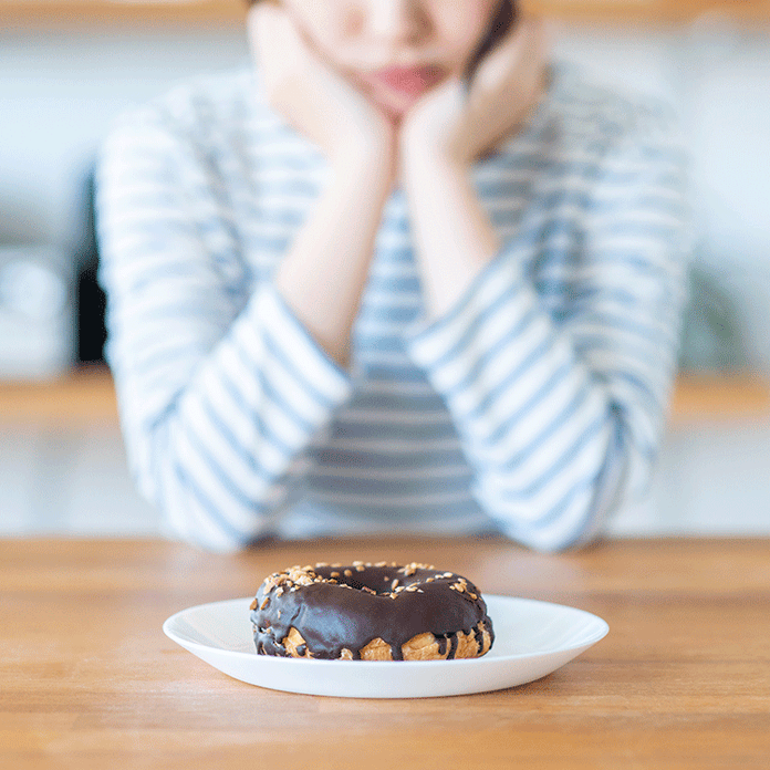 おやつを食べるのを悩む女性
